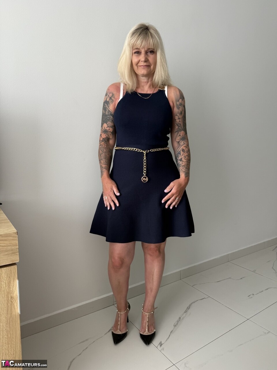 MILF blondă tatuată se dezbrăcă din rochie pe tocuri înalte
